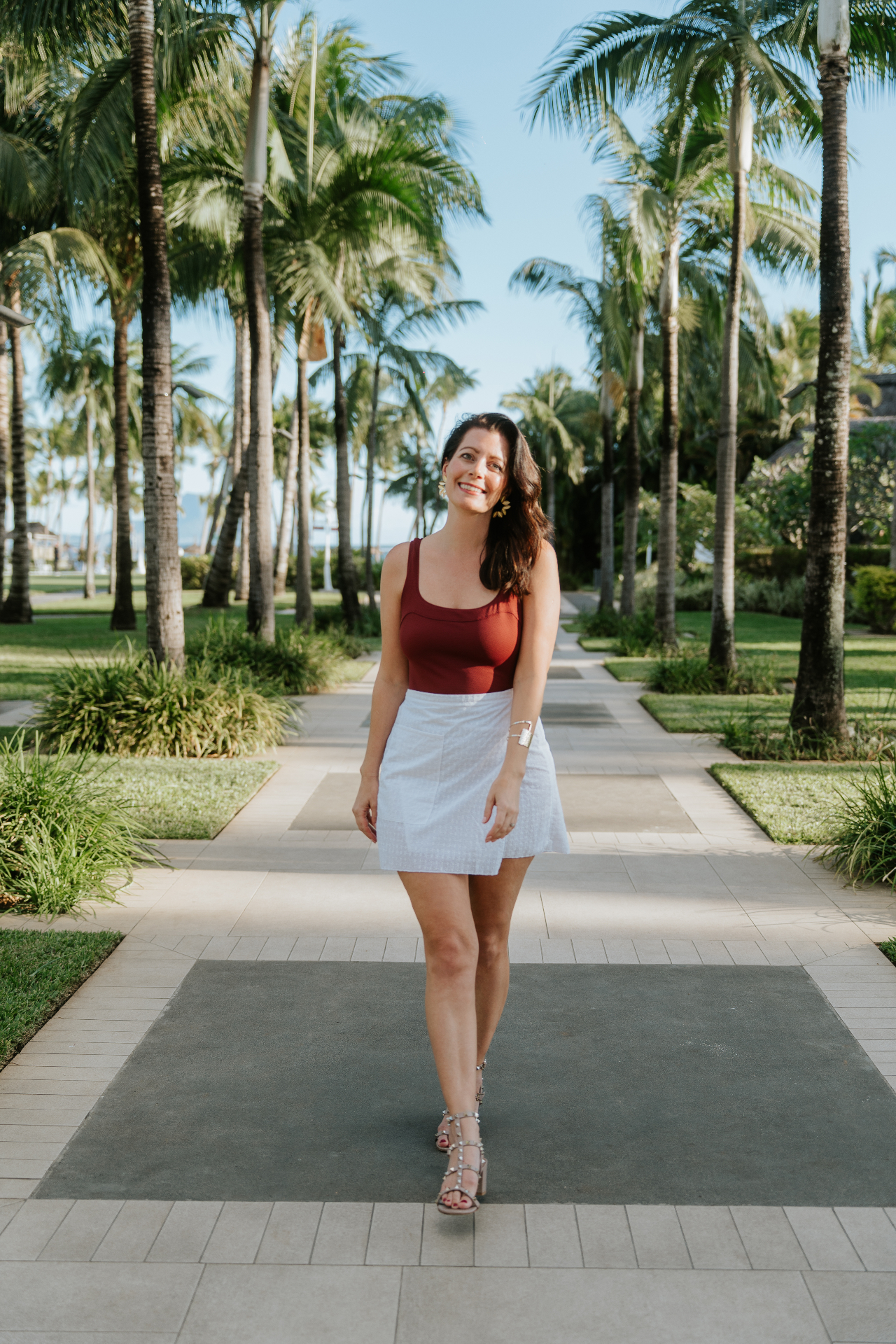Jennifer Constant walking through a palm-lined path